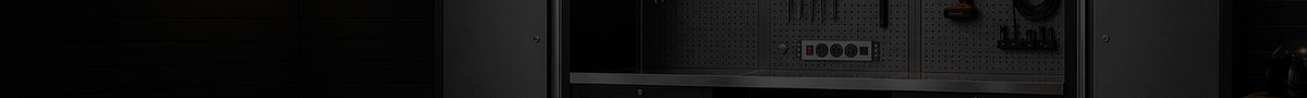 A close-up, low-angle view of a dark gray or black electronic device, showing a front panel with multiple ports and switches against a very dark background.