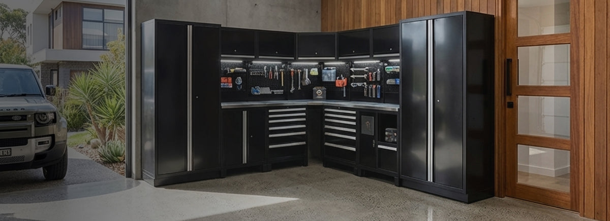 A modular black garage tool cabinet system with drawers, shelves, and a workbench, shown installed in a garage with a vehicle visible on the left.